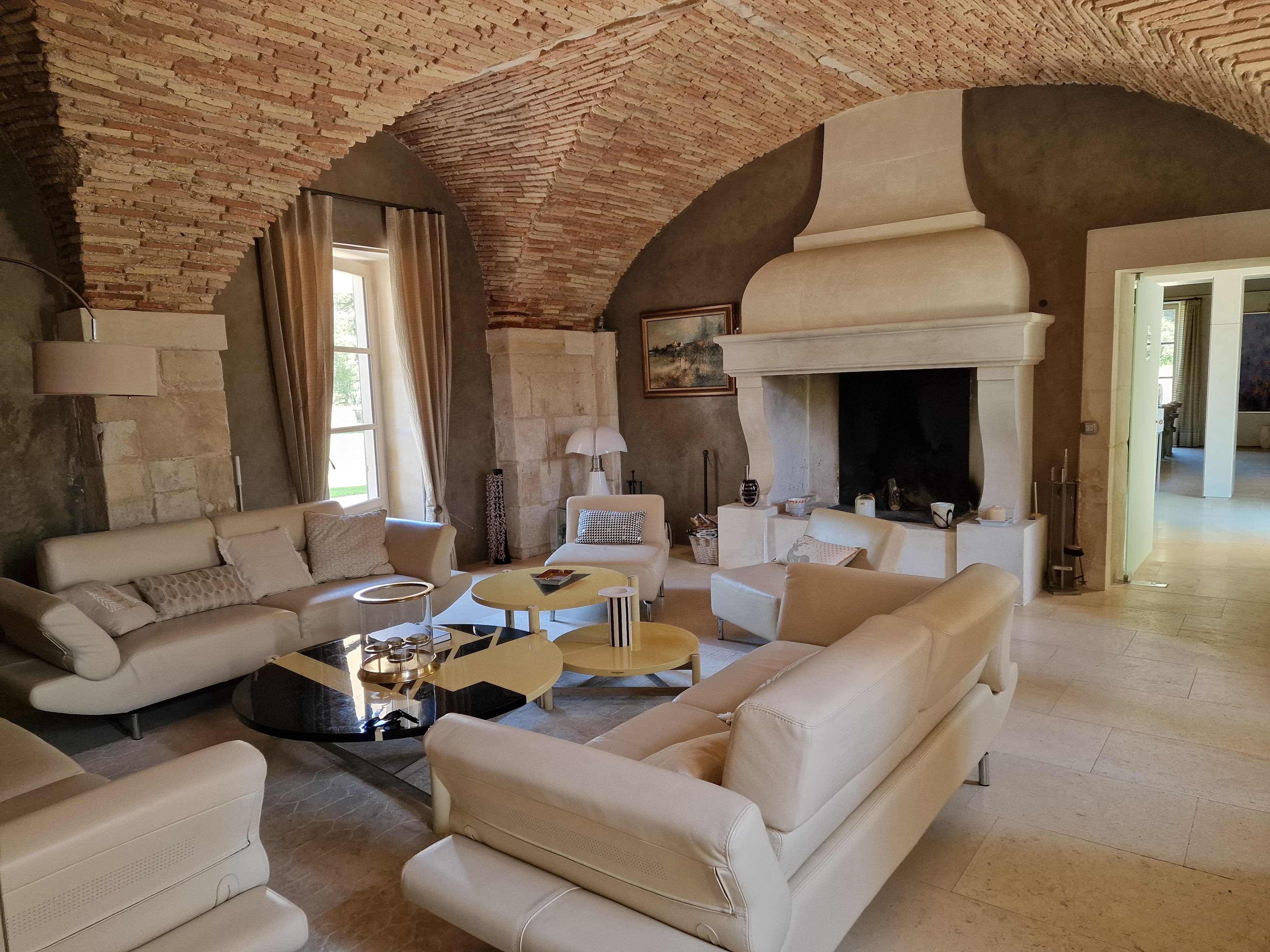 Living room under pale beams with a curved sofa and a wall sculpture