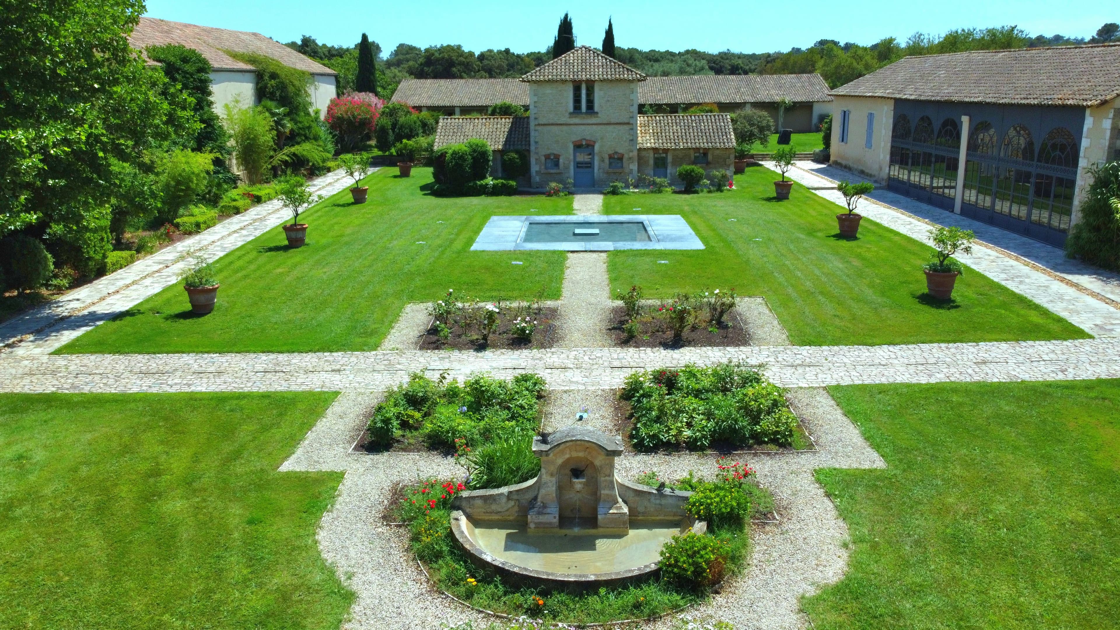 Estate courtyard with a basin, paved paths and rose beds