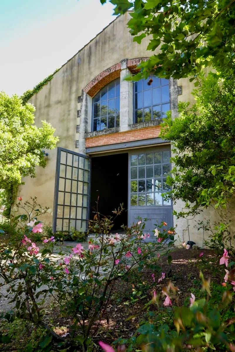 Stone façade with an arched bay and tall glazed doors, edged with rose bushes