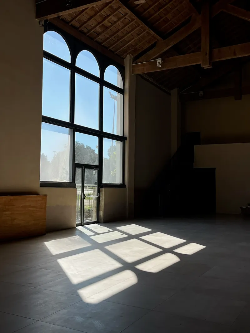 Arched window casting daylight across the floor of an empty hall