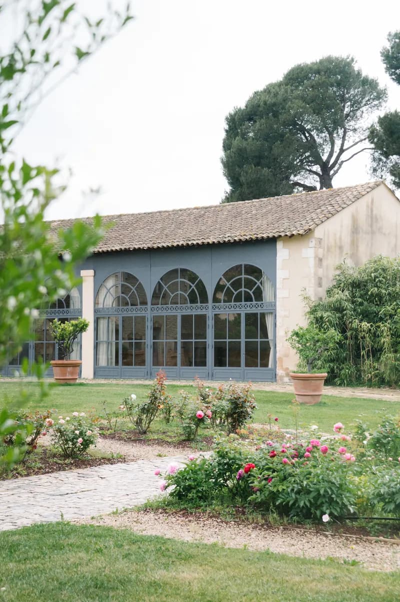 Arched glass windows of a reception building, in front of a rose garden in bloom