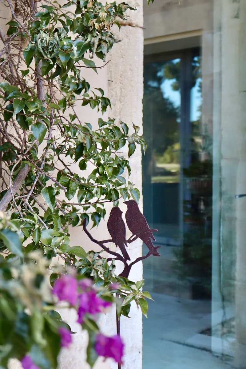 Metal bird ornament on a stone wall, among climbing foliage