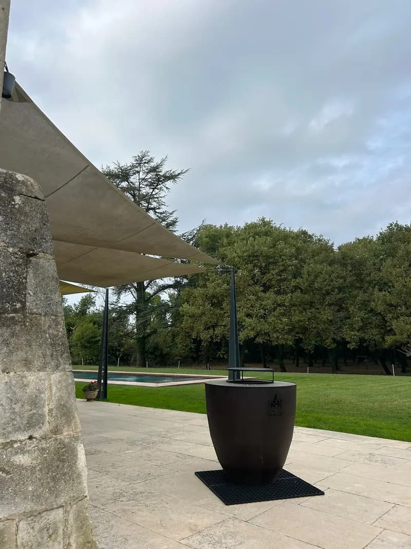 Fire pit on a stone terrace, under the shade sail facing the pool