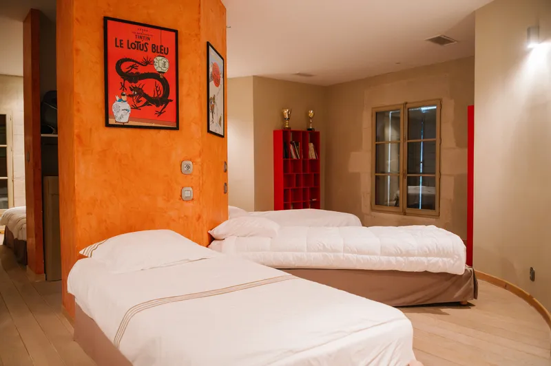 Bedroom with three single beds, an orange wall and framed posters