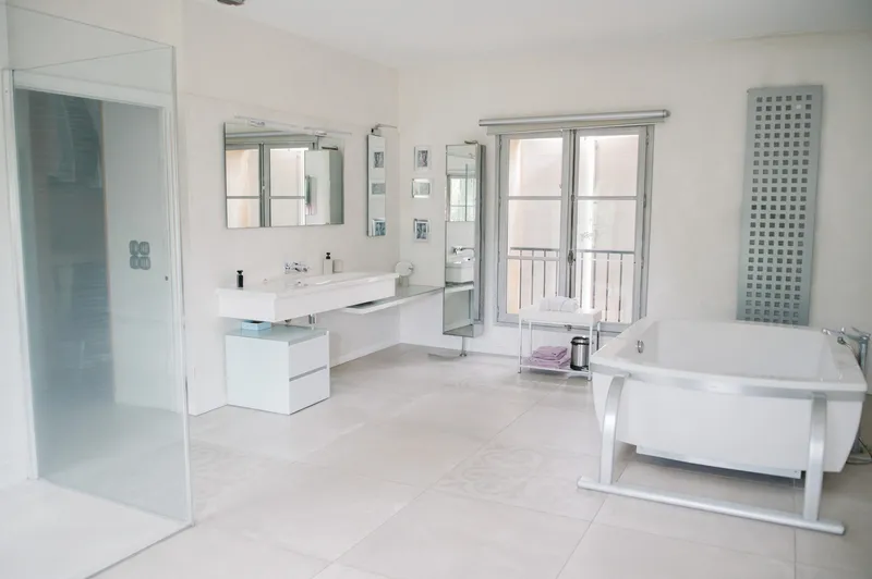 Bathroom with a double basin, freestanding bathtub and glazed shower