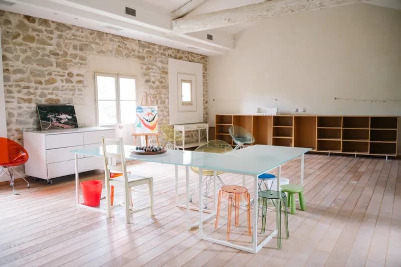 Common room with a large table, colourful stools and an exposed stone wall