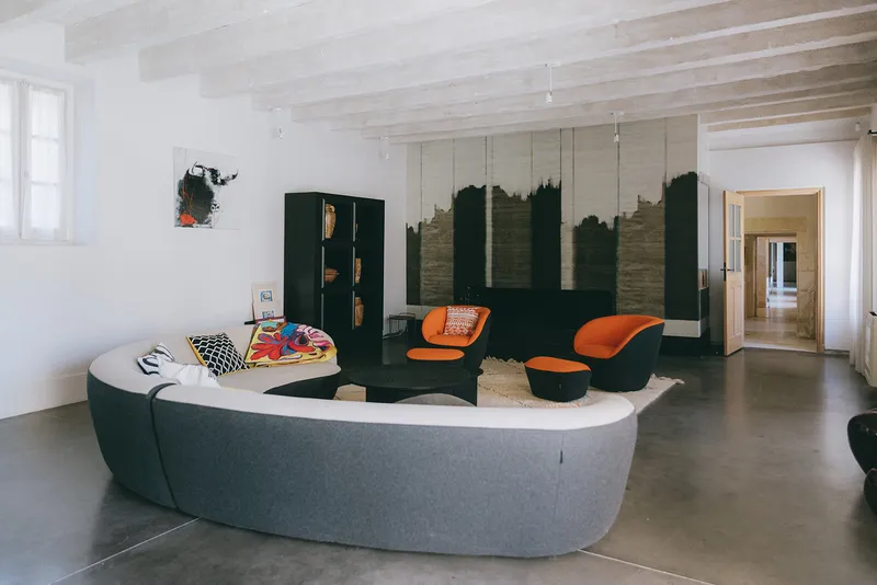 Contemporary living room with a curved sofa and orange armchairs on a concrete floor