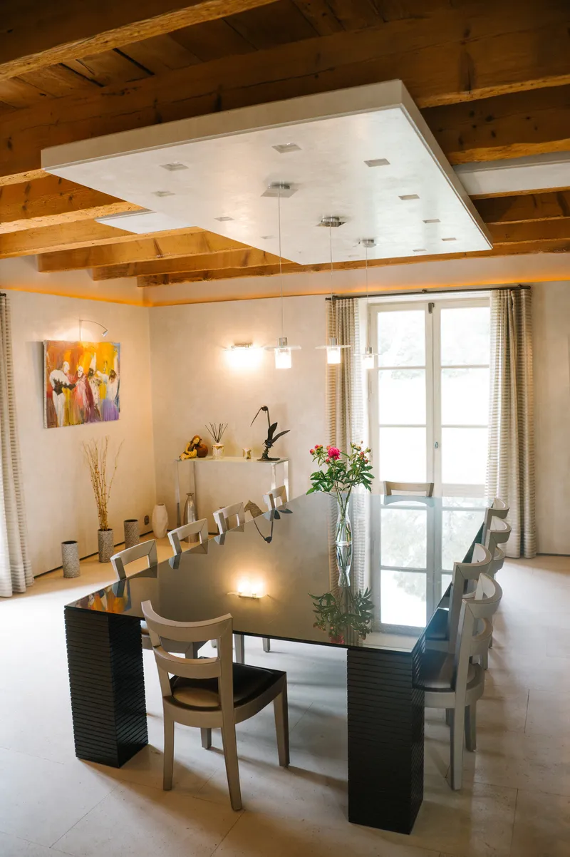 Dining room with a large table, a colourful painting and French doors onto the grounds