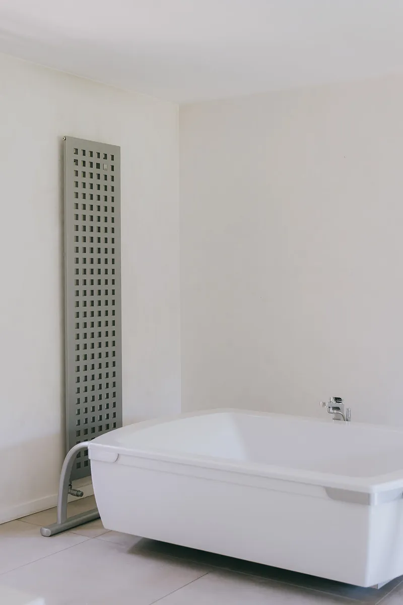 Freestanding bathtub in a white bathroom with a towel radiator