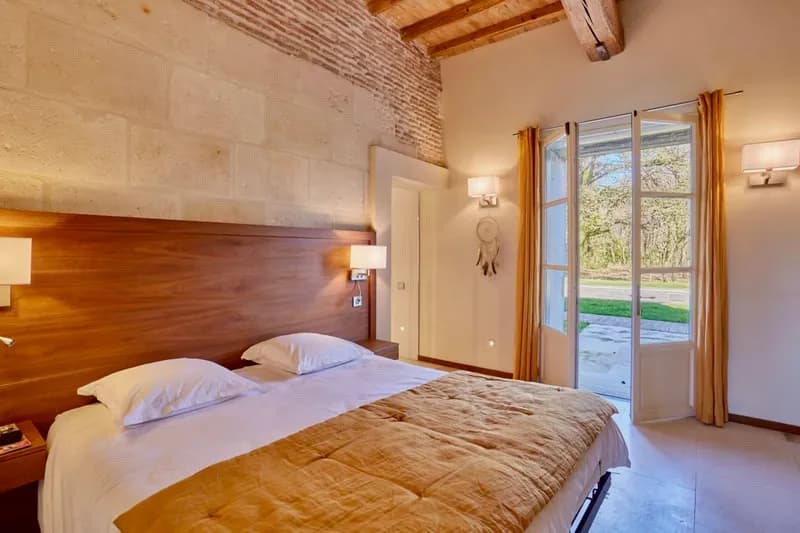 Stone-walled bedroom with a double bed and French doors opening onto the grounds