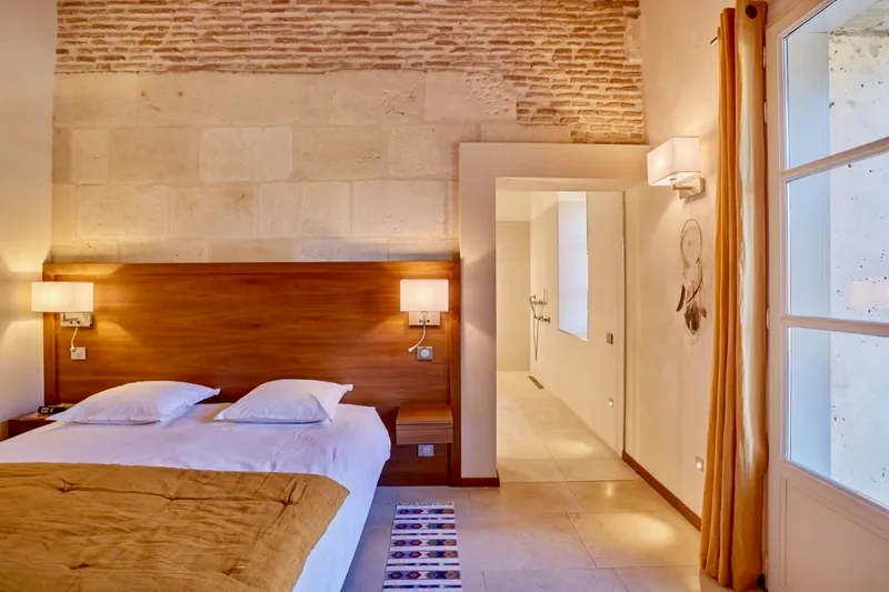 Stone bedroom with a wooden headboard and access to the shower room