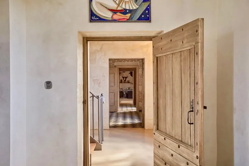 Wooden door opening onto a run of rooms with pale floors