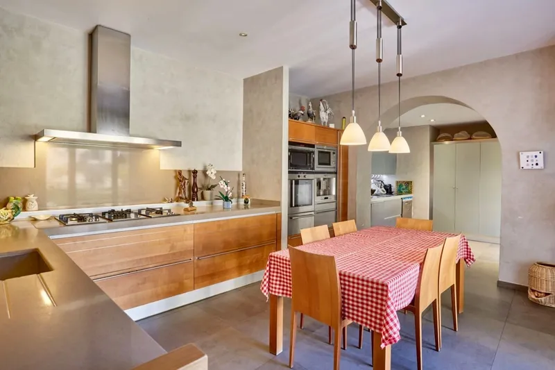 Fitted kitchen with an island, a stainless steel hood and a gingham-clothed table