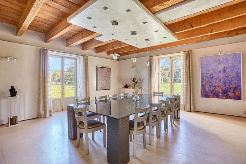 Dining room under pale beams, opening onto the grounds through two French doors