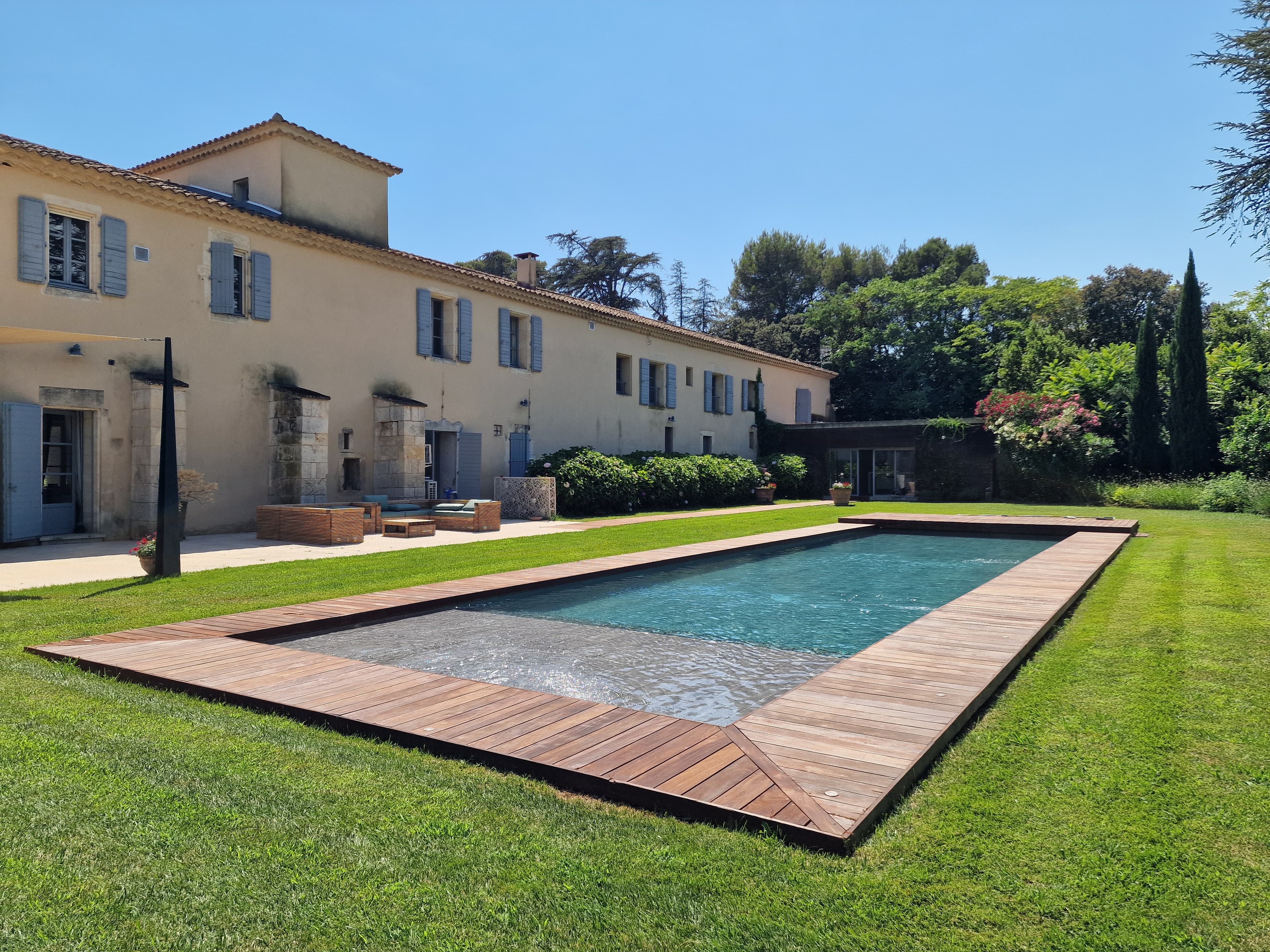 Estate pool edged with a wooden deck, facing the grounds